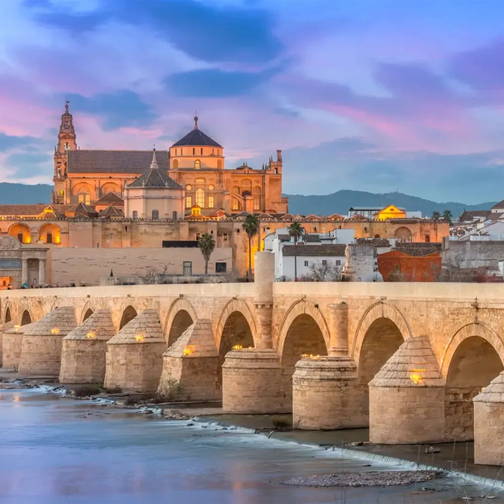 El Puente Romano de Córdoba sobre el Guadalquivir, con la Mezquita-Catedral al fondo al atardecer