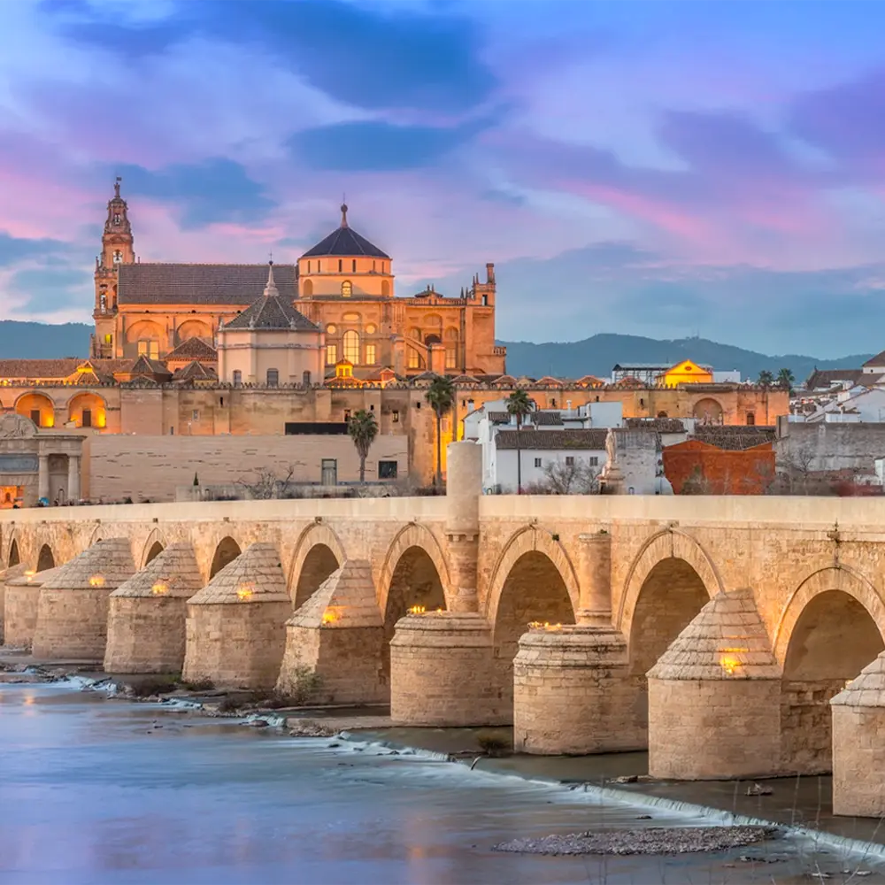 El Puente Romano de Córdoba sobre el Guadalquivir, con la Mezquita-Catedral al fondo al atardecer